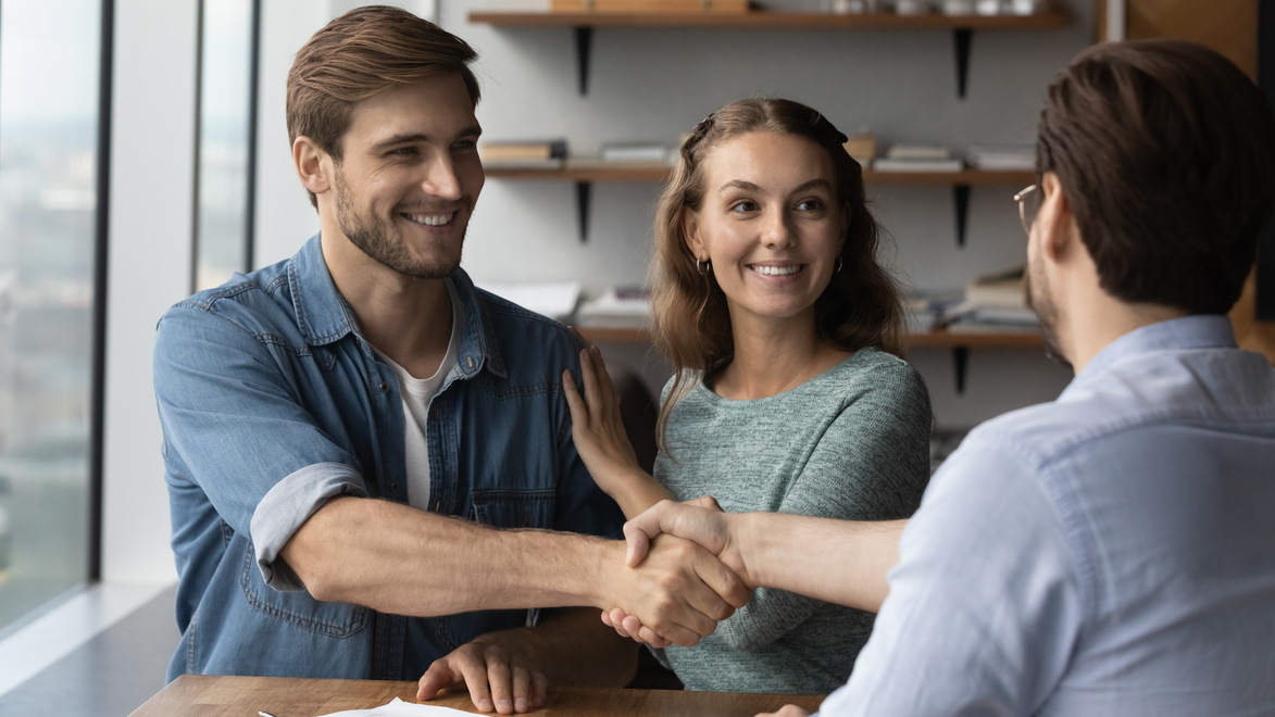 Happy couple clients handshake relator at meeting